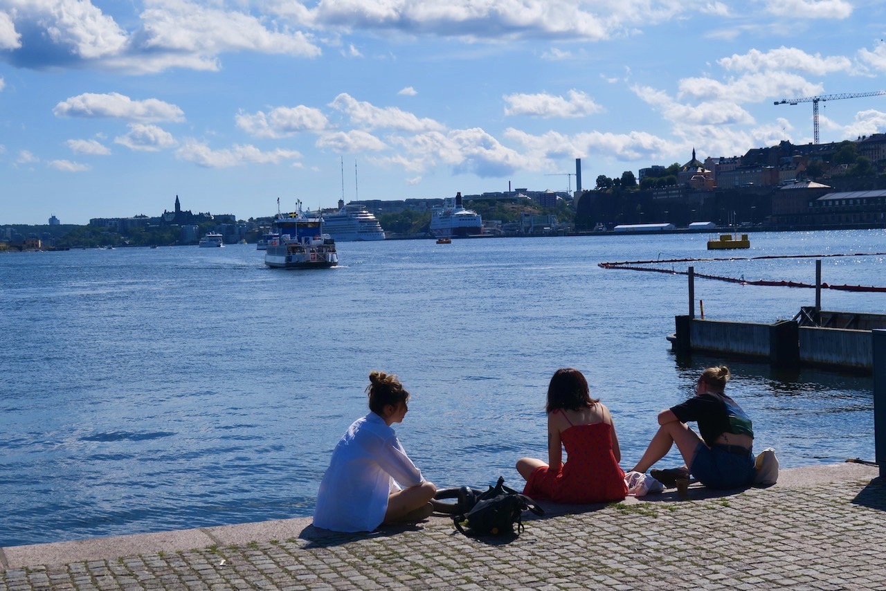 Stockholm i dag. Strålande sommarväder med +27. här har några slagit sig ner vid kajkanten på Skeppsbron. 